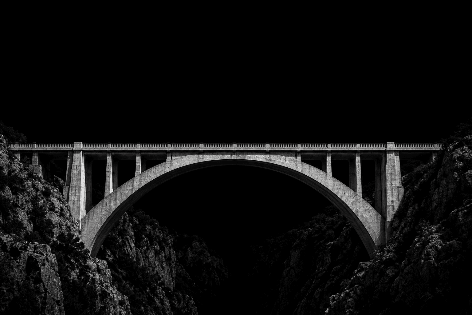 A concrete arch bridge spanning a rocky ravine